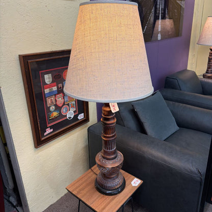 Decorative lamp on a side table next to a gray sofa with a framed picture on the wall.
