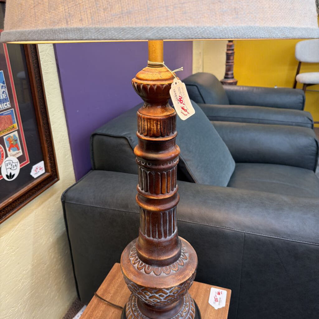 Decorative lamp with a tag on a surface in a room with furniture and decor.