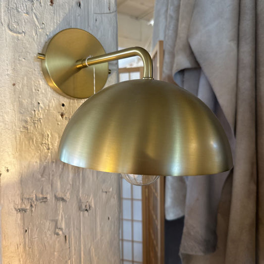 Gold wall sconce mounted on a wooden wall