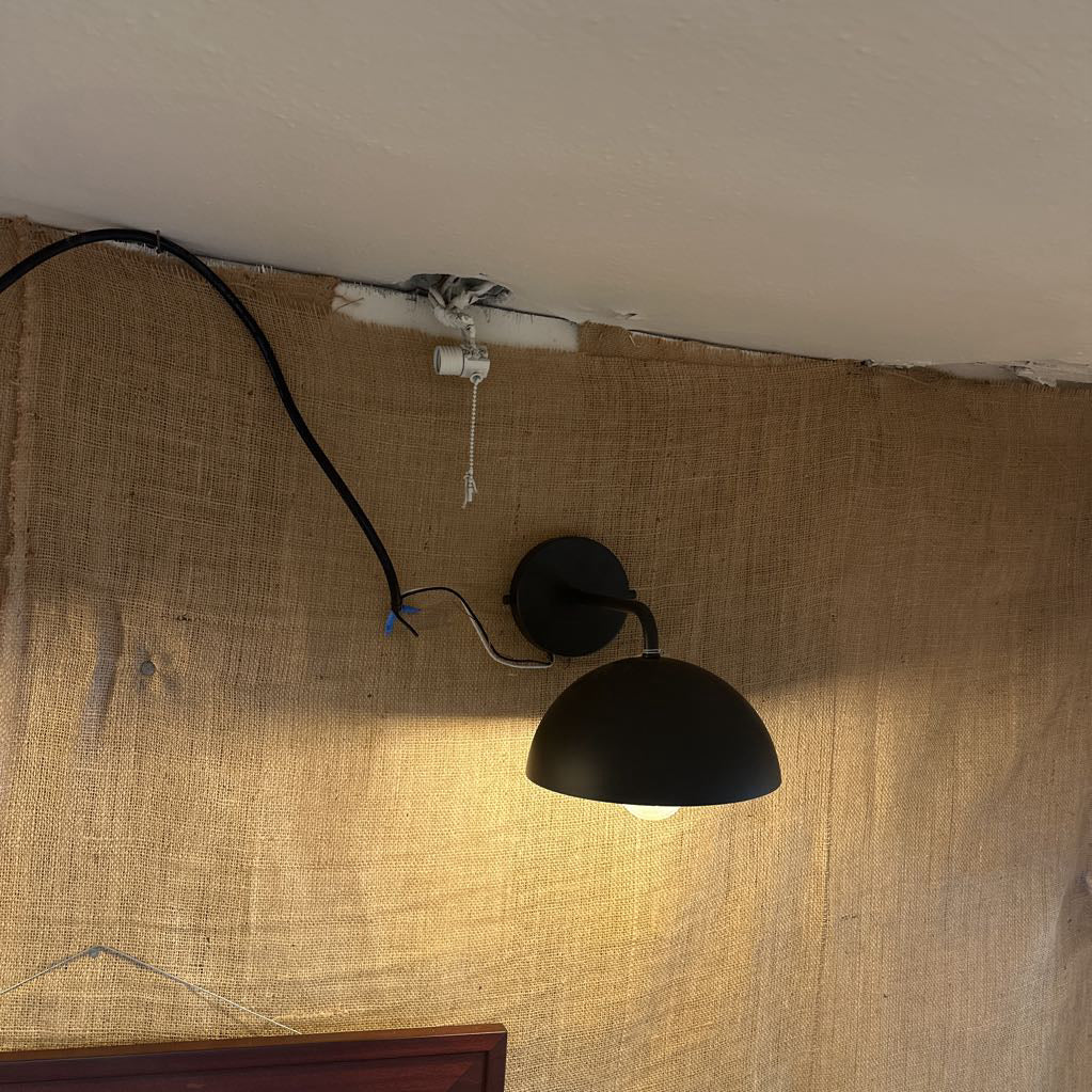 Black wall-mounted lamp on a textured beige wall