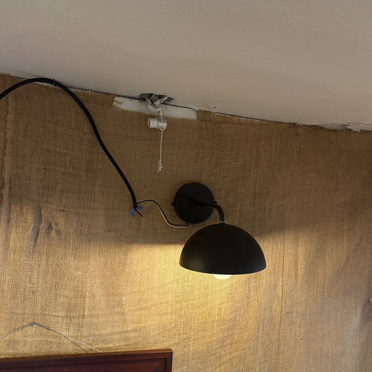 Black wall-mounted lamp on a textured beige wall