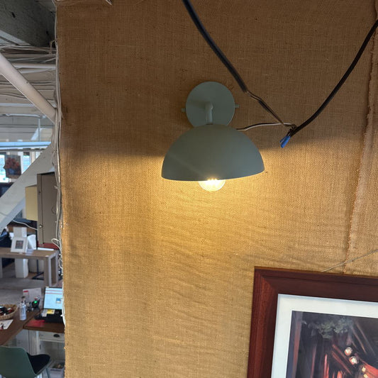 Wall-mounted light fixture on a textured wall with a room in the background