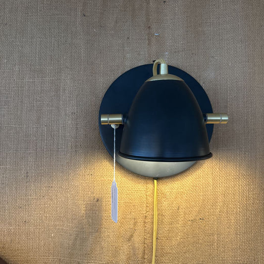 Wall-mounted lamp with a dark blue shade and gold accents on a textured beige wall.