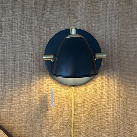Wall-mounted lamp with blue shade and gold accents on a textured brown background