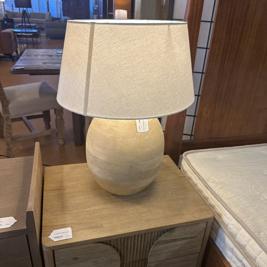 Beige table lamp on a wooden table with a blurred indoor setting