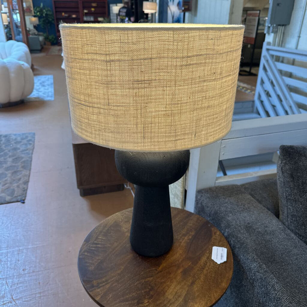 Table lamp with a woven shade on a wooden base in a room setting