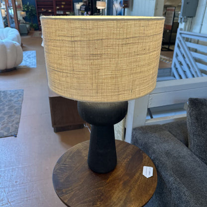 Table lamp with a woven shade on a wooden base in a room setting