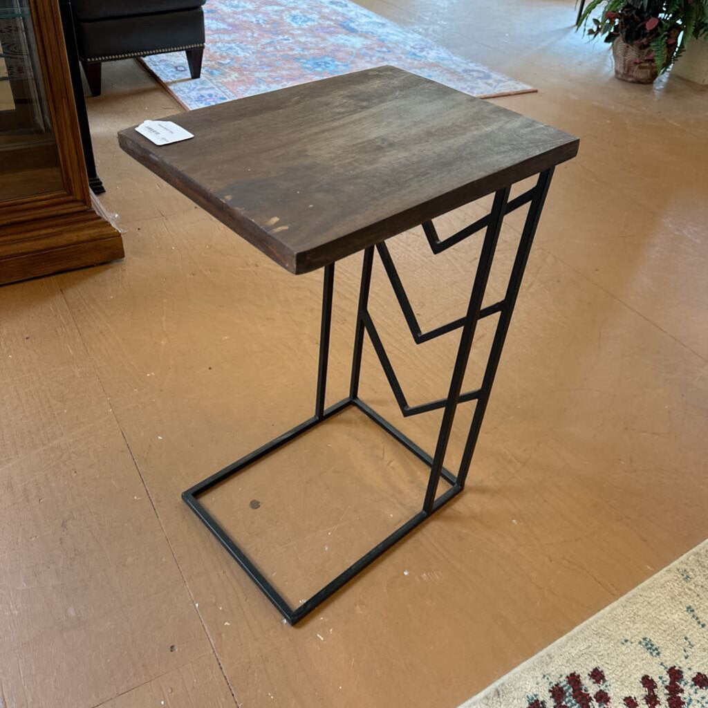 Wooden side table with black metal frame on a wooden floor