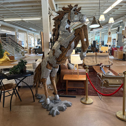 Large metallic horse sculpture in a showroom setting with furniture and decor.