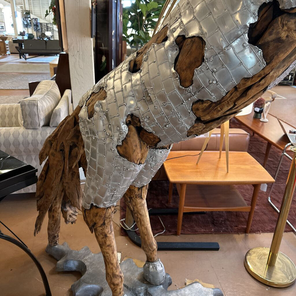 Large metallic horse sculpture in a showroom setting with furniture and decor.