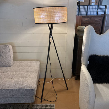 Floor lamp with a woven shade in a living room setting.