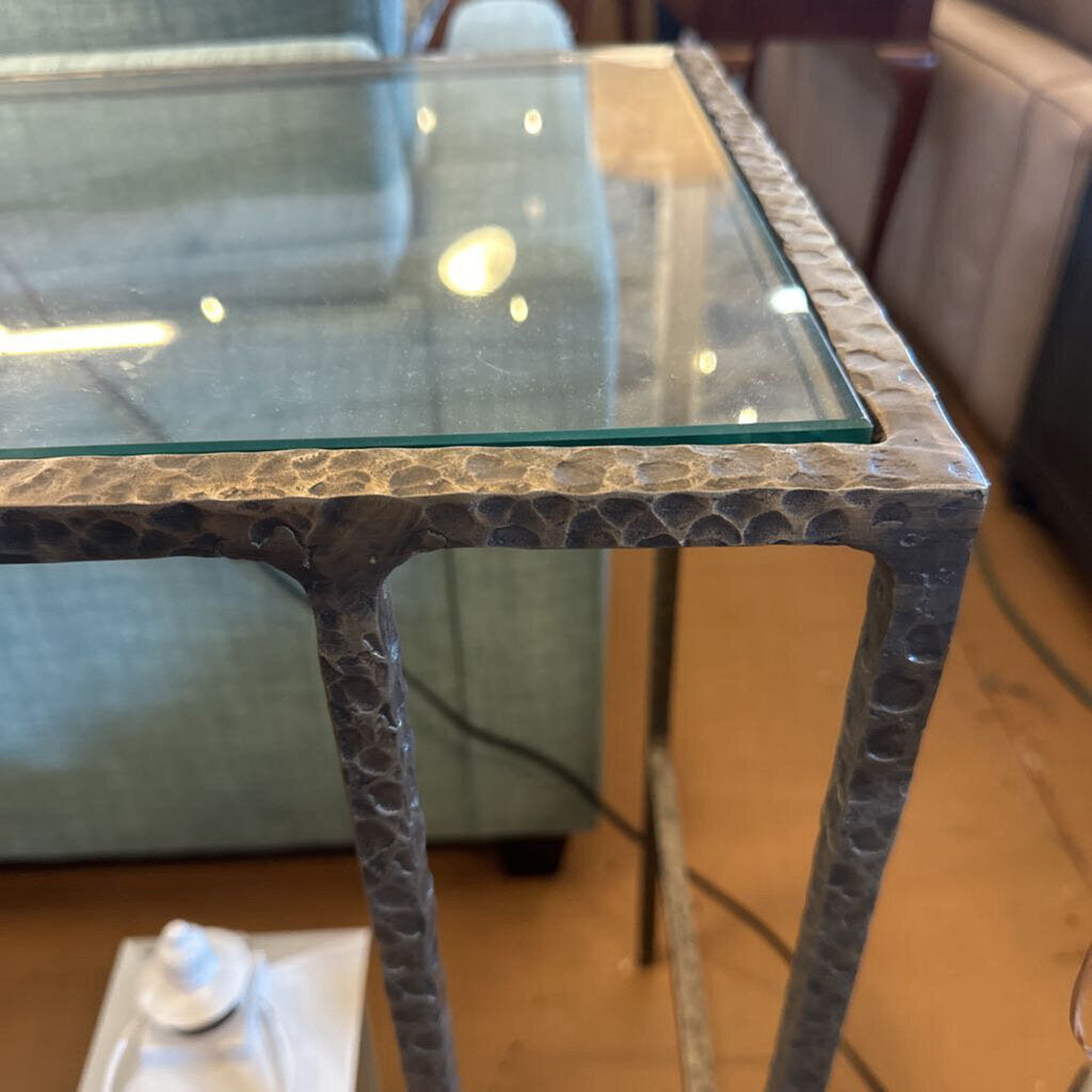 Glass-top table with textured metal base in a room setting