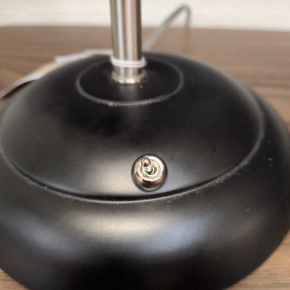 Close-up of a black lamp base with a metallic socket on a wooden surface.