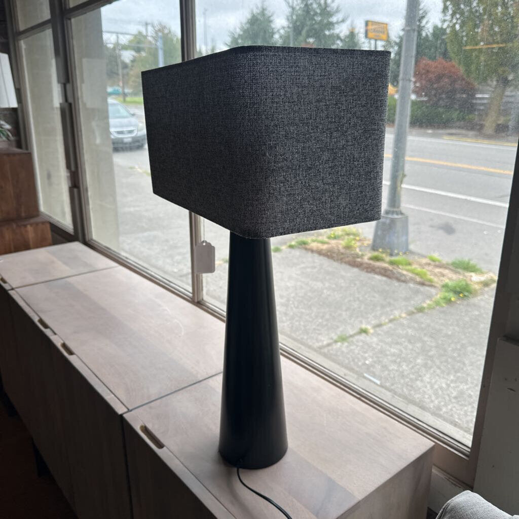 Black table lamp with a textured shade on a windowsill