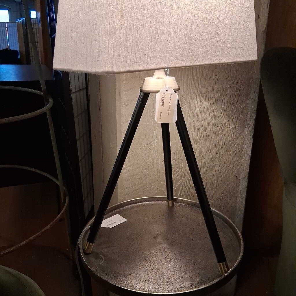 Tripod-style floor lamp with a textured white shade on a metal base.