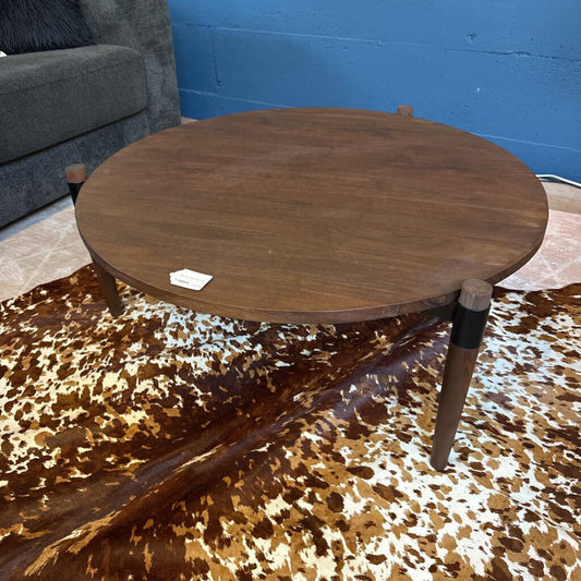Wooden round table on a patterned rug with a blue wall background