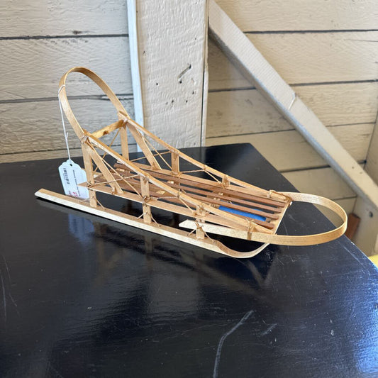 Wooden sled on a black surface with a wooden background