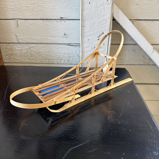 Wooden sled on a black surface with a wooden wall background