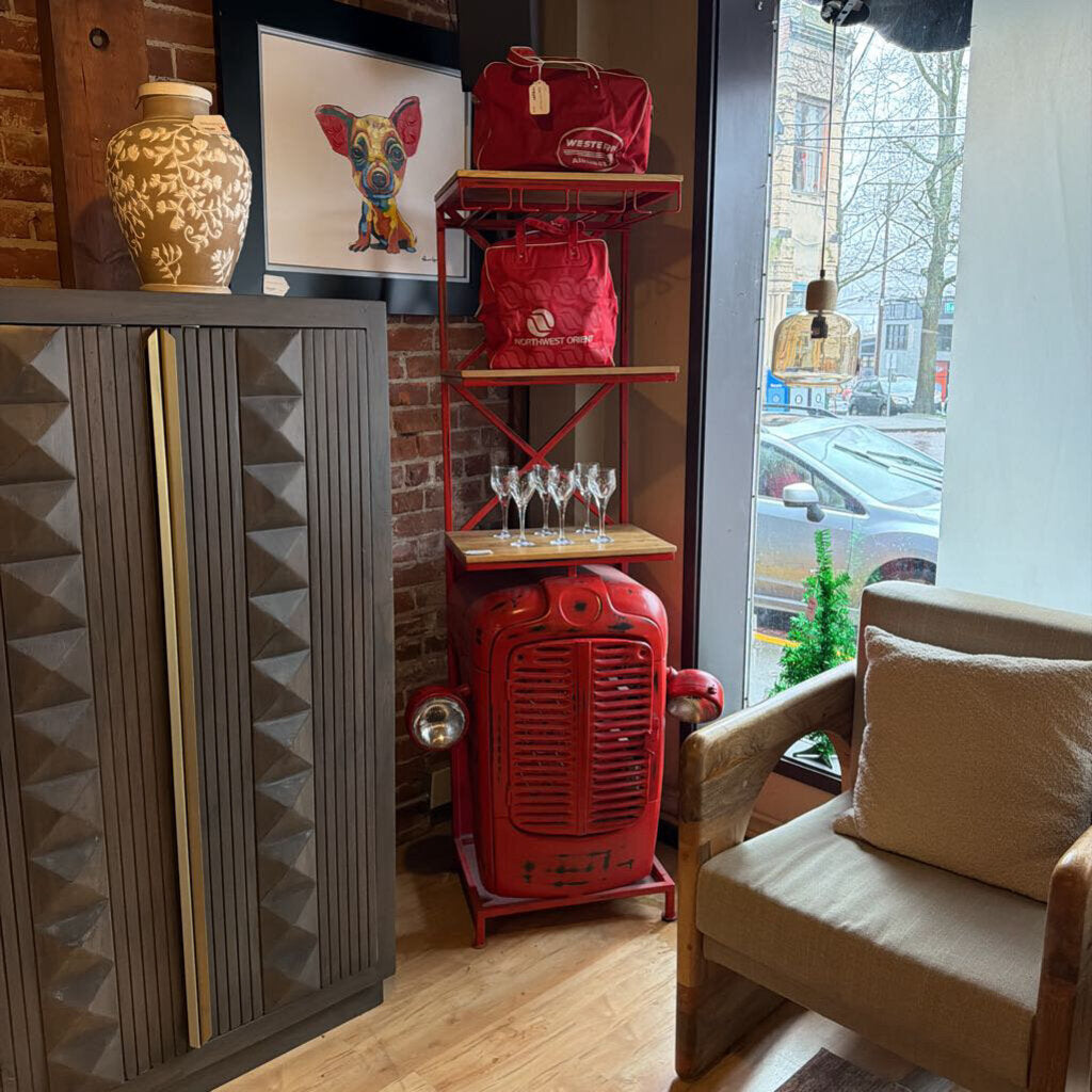 Interior of a cafe with red bags on a shelf, a painting of a dog, and a chair with a pillow.