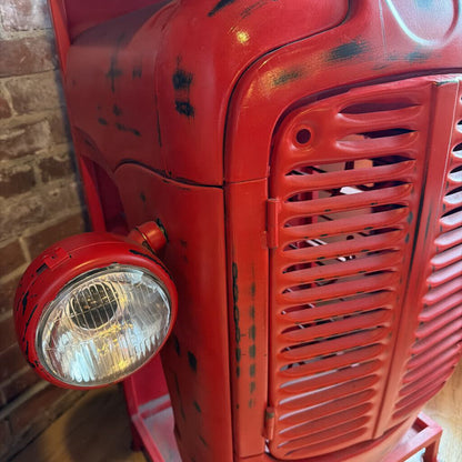 Close-up of a red vintage vehicle with a headlight against a brick wall.