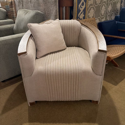 Beige armchair with a pillow in a room with other furniture.