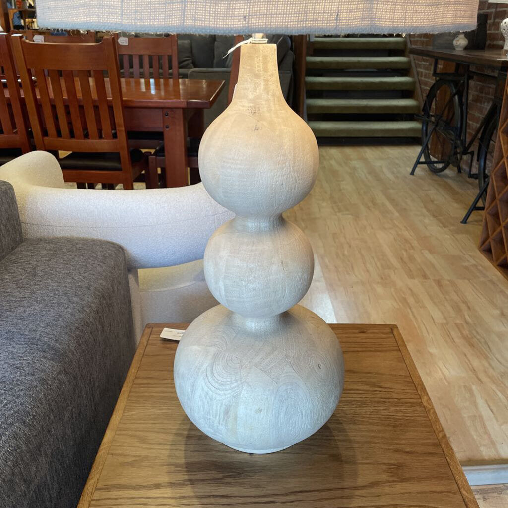Decorative lamp on a wooden table in a room with furniture and stairs.