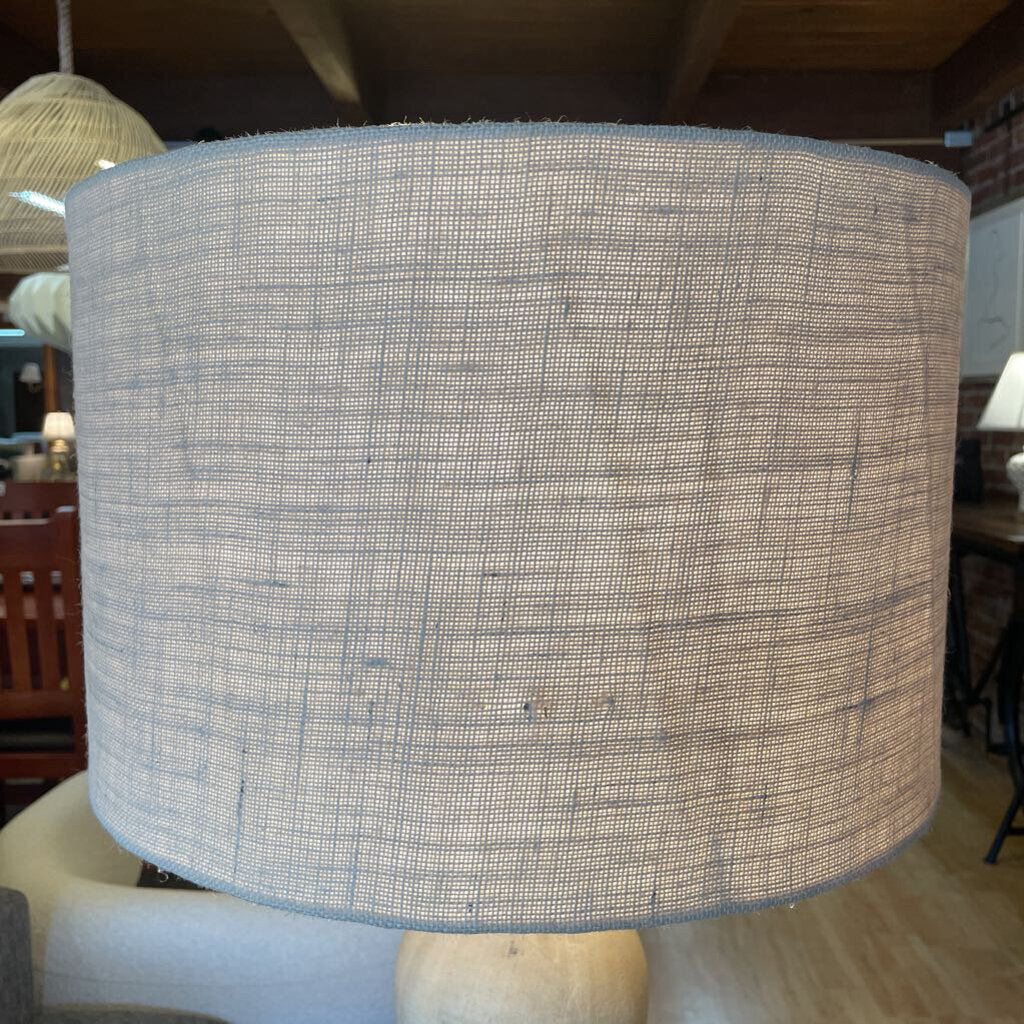 Textured lampshade in a room setting with furniture and decor.