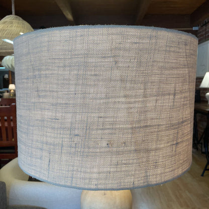 Textured lampshade in a room setting with furniture and decor.