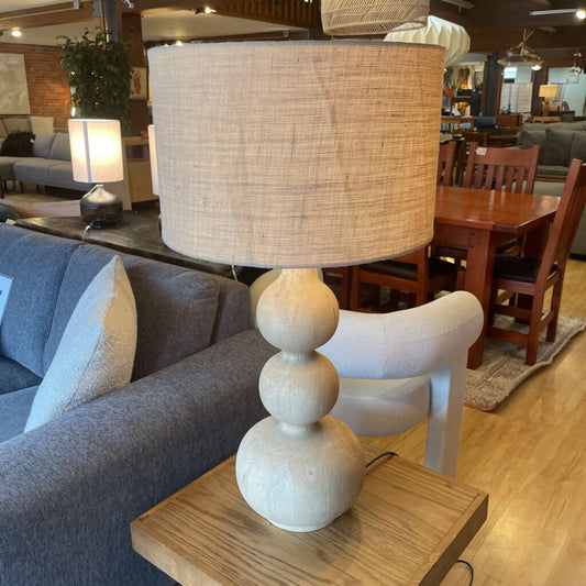 Decorative lamp with wicker shade on a wooden table in a living room setting.