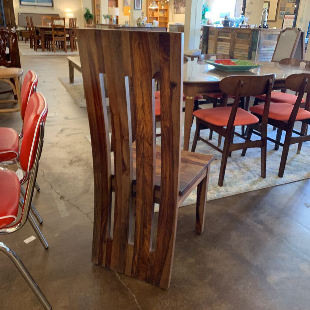 Wooden dining table with red chairs in a showroom setting