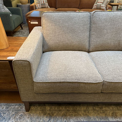 Gray sectional sofa in a room with furniture and decor.