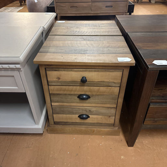 Wooden nightstand with three drawers in a furniture store setting