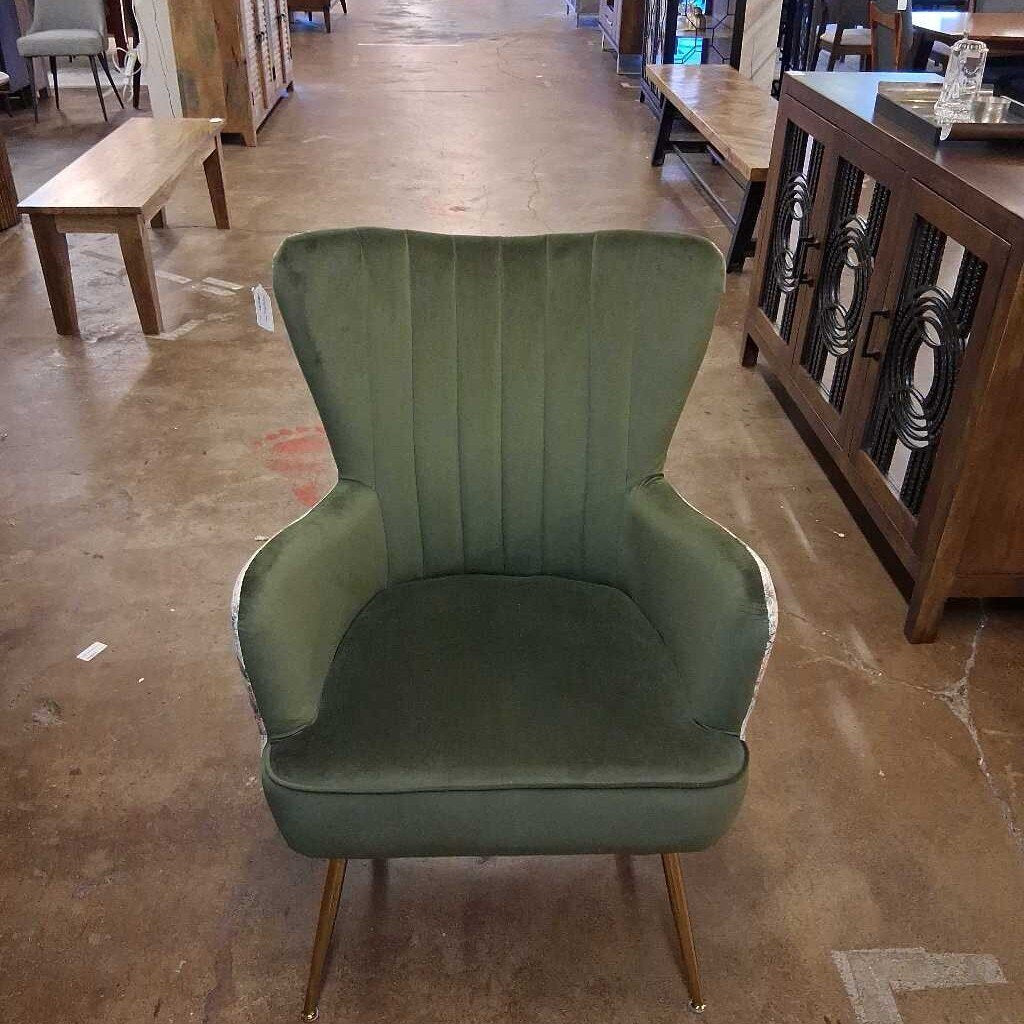 Green armchair in a store setting with wooden furniture and flooring.