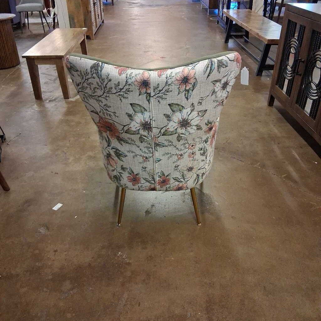 Floral-patterned chair in a store setting with other furniture items.