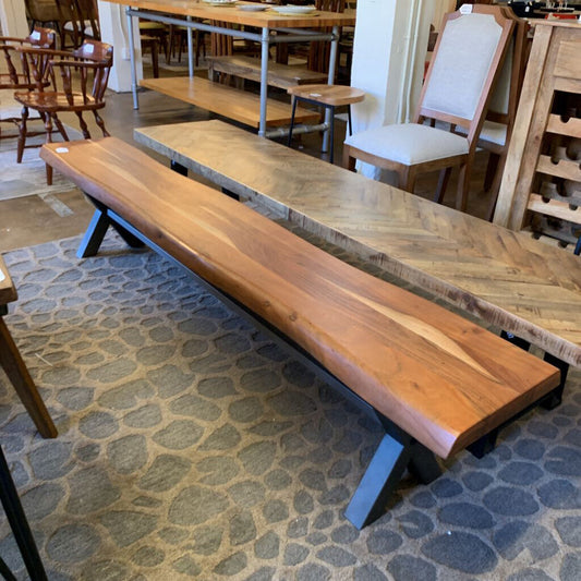 Long wooden bench with metal legs on a stone floor in a dining area.
