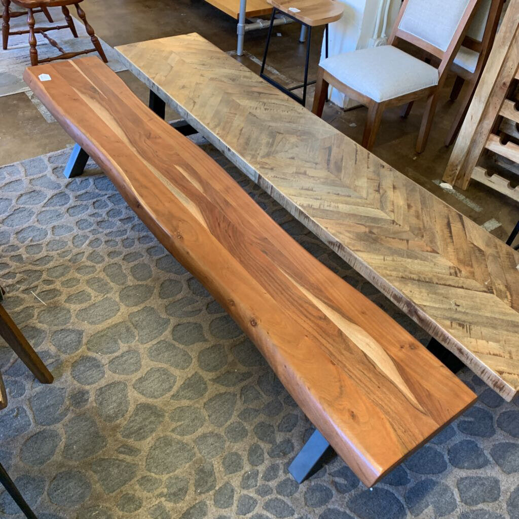 Wooden bench and table in a store setting with stone floor and chairs in the background