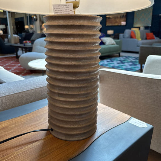 Decorative lamp with ribbed base on a table in a room with furniture and decor.