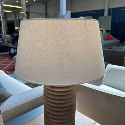 Beige lampshade on a textured brown base in an indoor setting