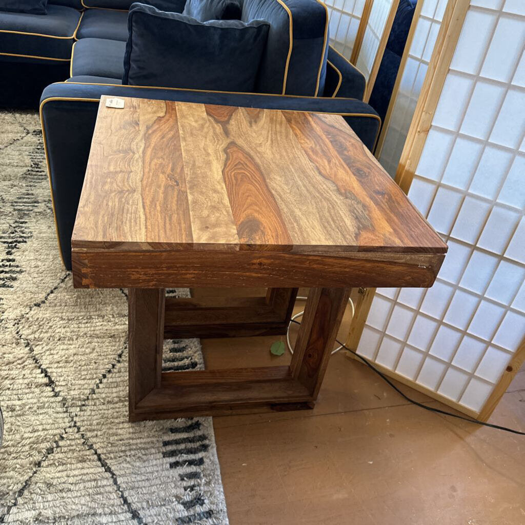 Wooden side table in a room with a rug and wall art
