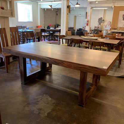 Large wooden dining table in a room with chairs and other tables.