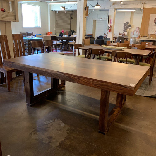 Large wooden dining table in a room with chairs and other tables.