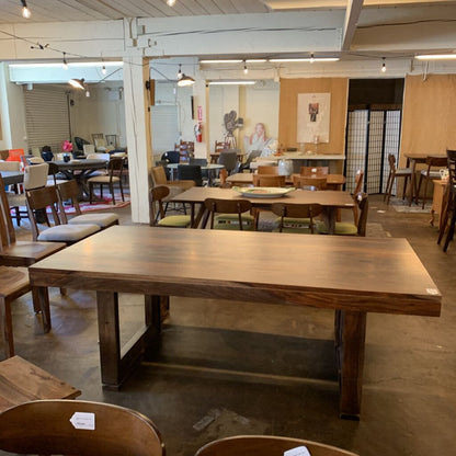 Wooden dining table in a showroom with chairs and other furniture.