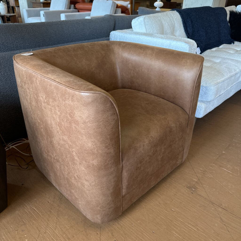 Brown leather armchair in a showroom setting with other furniture.