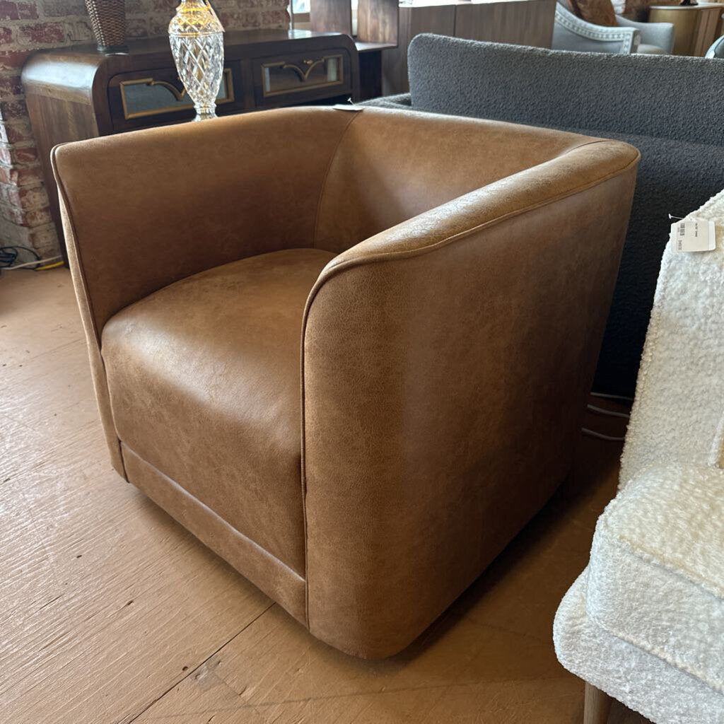 Brown leather armchair in a room with wooden floor and other furniture.