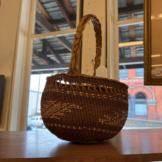 Woven brown basket on a wooden surface with a blurred indoor background
