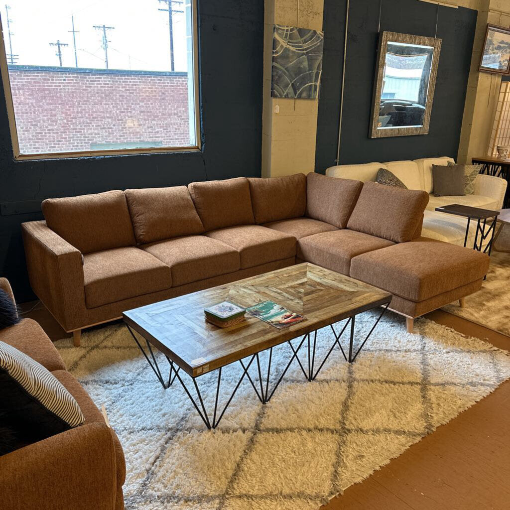 Brown sectional sofa in a living room with a coffee table and decorative items.