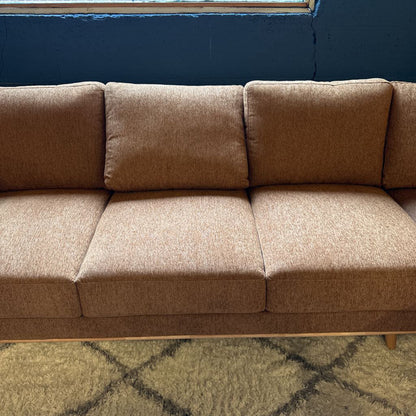 Brown sofa against a blue wall with a patterned rug on the floor.