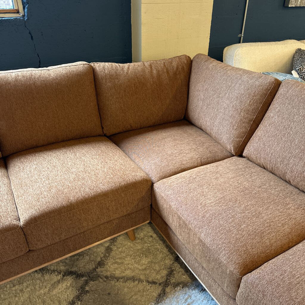Brown sectional sofa in a room with a blue wall and a window.