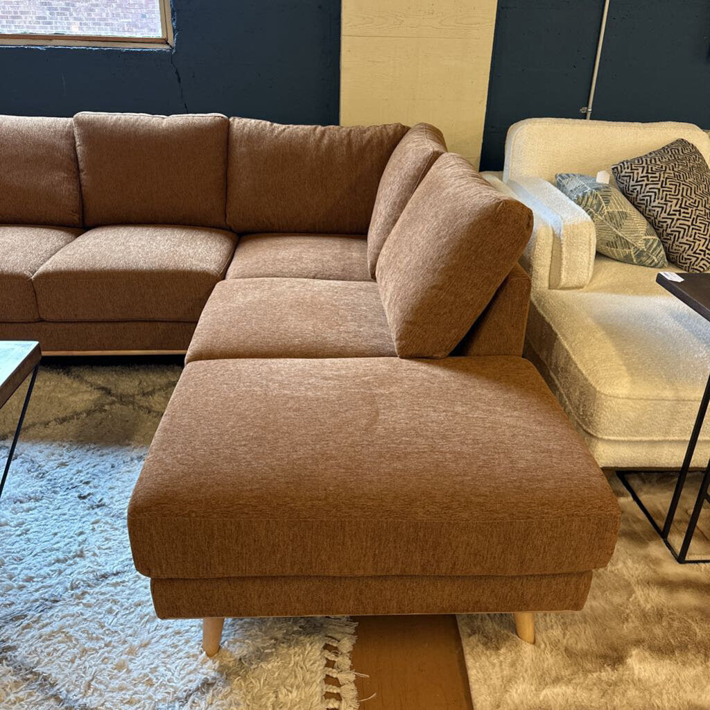Brown sectional sofa in a living room setting with a beige armchair and coffee table.