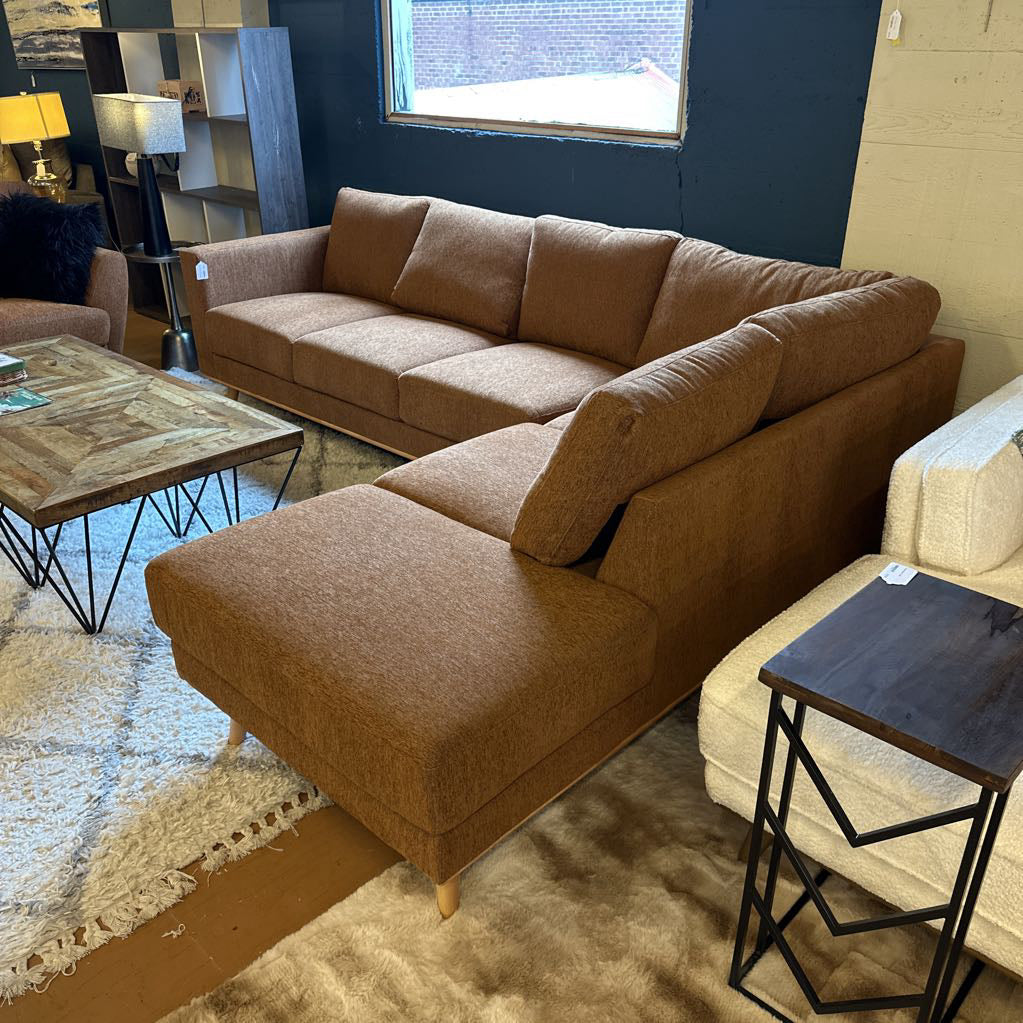 Brown sectional sofa in a room with a coffee table and decorative items.